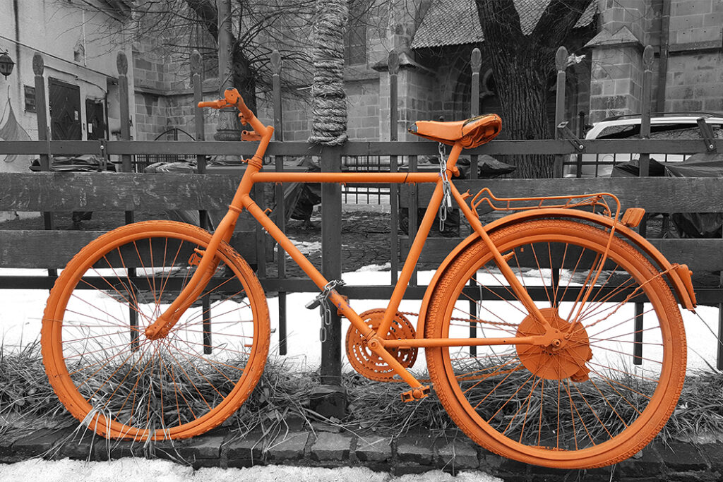 Orange vintage bicycle chained to a fence near the Black Church in Brasov